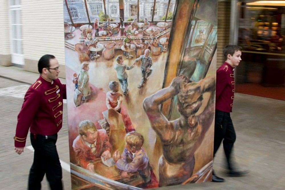 Hotelpagen tragen ein Gemälde des Grand Elysee auf dem Gehsteig von Hamburg