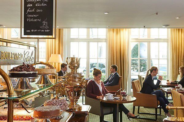 Blick ins Boulevard Cafè des Grand Elysee mit angerichteten Torten und entspannten Gästen im Hintergrund