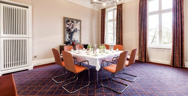 Konferenzraum mit blauem Teppichboden und einem gedeckten Tisch für acht Personen in Hamburg